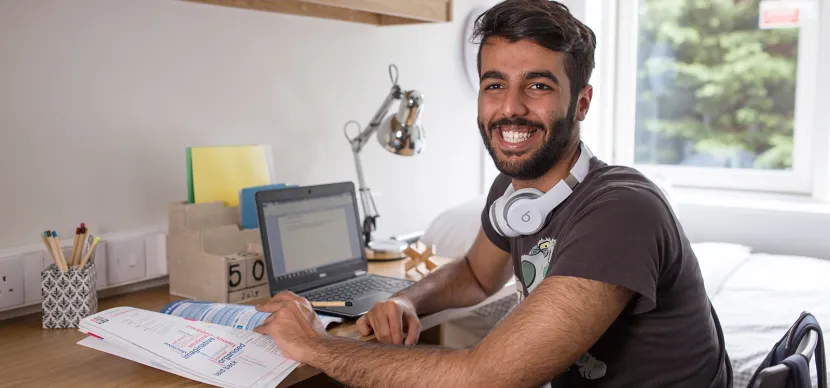 student working on his laptop in his room