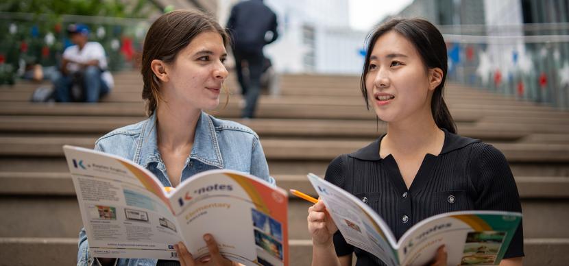 two students looking at brochure on stairs