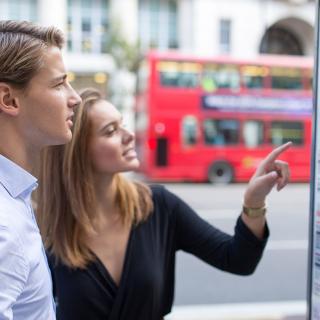 students looking at bus timetable in London