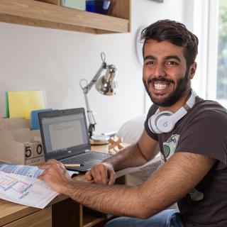 student working on his laptop in his room